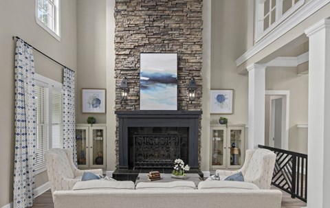 A living room with a stone fireplace and a painting above it.